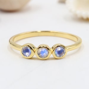 May include: A gold ring with three round moonstone gems. The ring is simple and elegant.