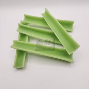 May include: Five green, plastic, celery sticks. The sticks are all the same size and shape, and they are arranged in a pile.