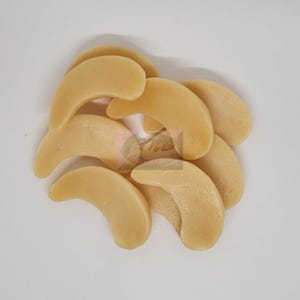 May include: A close-up of a pile of light brown, crescent-shaped, gummy candies.