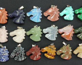 Puede incluir: Una colección de 18 colgantes de cabeza de caballo tallados en varios tipos de piedras preciosas, incluyendo cuarzo rosa, ojo de tigre y turquesa. Cada colgante presenta una argolla de plata para una fácil fijación a un collar o pulsera.