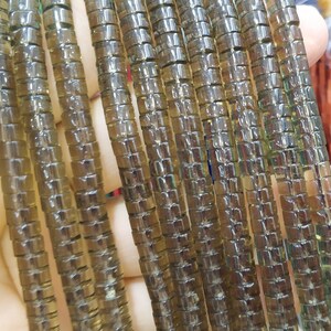 May include: A strand of brown glass beads, each bead is made up of small square-shaped pieces of glass. The beads are strung together to form a long strand.