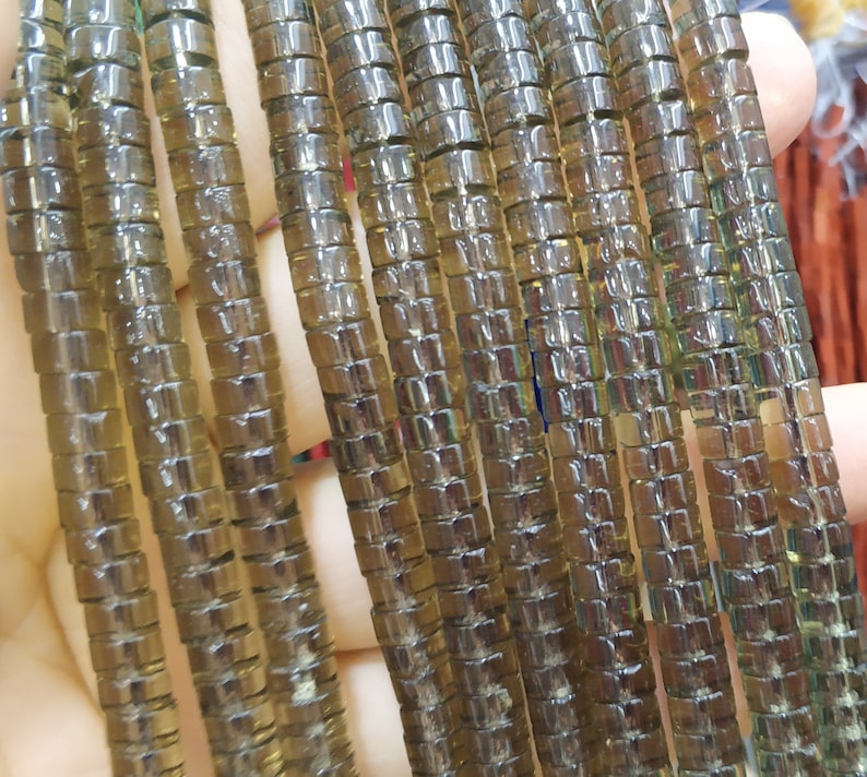May include: A strand of brown glass beads, each bead is made up of small square-shaped pieces of glass. The beads are strung together to form a long strand.