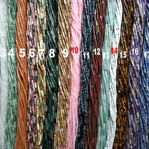 Puede incluir: Diecinueve hebras de cuentas de piedras preciosas de diferentes colores, cada hebra numerada del 1 al 19. Las cuentas son todas cilíndricas y tienen un acabado liso y pulido.