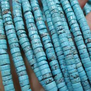 May include: A strand of turquoise beads, each bead is a cylinder with a light blue color and a mottled pattern. The beads are strung together on a clear thread.