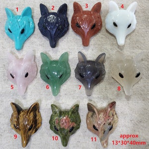 Op de afbeelding: Tien vossenkop-beeldhouwwerken in verschillende kleuren en materialen, waaronder turquoise, zwart, rood, wit, roze, groen, grijs, bruin en groen en rood. Elk beeldhouwwerk is ongeveer 13 mm bij 30 mm bij 40 mm.