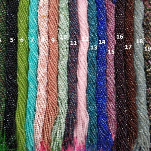 Op de afbeelding: Een selectie van 22 strengen edelsteen kralen, elke streng is ongeveer 38 cm lang. De kralen zijn gefacetteerd en variëren in kleur van lichtblauw tot donkerpaars.