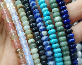 May include: Assortment of gemstone beads in various colors, including pink, white, green, blue, and black. The beads are round and smooth, and they are arranged in rows on a hand.