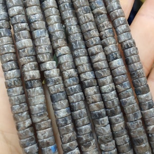 May include: A strand of gray and black gemstone beads, each bead is a cylinder with a square cross-section.