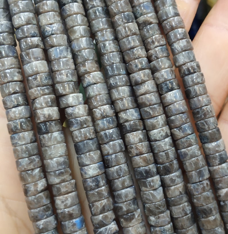 May include: A strand of gray and black gemstone beads, each bead is a cylinder with a square cross-section.