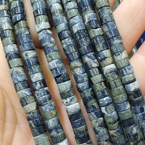 May include: A strand of black and green gemstone beads. The beads are round and have a marbled pattern.