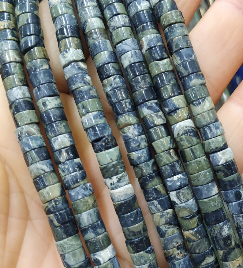May include: A strand of black and green gemstone beads. The beads are round and have a marbled pattern.