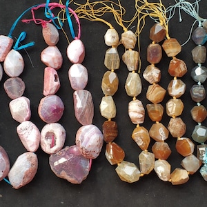 Peut inclure: Plusieurs colliers de pierres précieuses aux couleurs variées, notamment bleu, rose, marron et gris. Chaque collier est composé de perles de forme irrégulière enfilées sur un fil coloré.