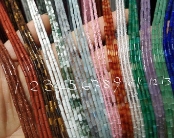 May include: A close-up of 14 strands of different colored gemstone beads. The beads are all cylindrical and have a smooth, polished finish. The colors of the beads are: red, brown, white, green, pink, orange, clear, green, purple, green, blue, and blue. The beads are numbered 1 through 14.