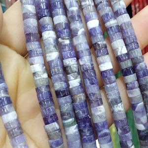 May include: A strand of purple and white amethyst beads, each bead is a square cylinder shape.