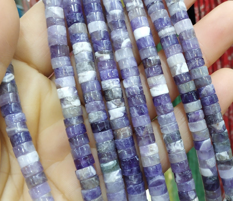 May include: A strand of purple and white amethyst beads, each bead is a square cylinder shape.