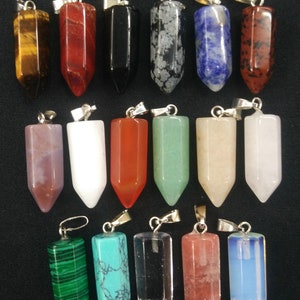 Può includere: Una collezione di 18 ciondoli in pietra preziosa, ognuno con un'anellina in argento. I ciondoli sono di varie forme e colori, tra cui rosso, blu, verde, nero, bianco e marrone.
