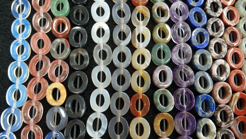 Puede incluir: Una hebra de cuentas de piedras preciosas en forma de rosquilla en varios colores, incluidos azul, verde, morado, rojo, marr&oacute;n y blanco. Las cuentas est&aacute;n enhebradas en un alambre y est&aacute;n listas para usarse en la elaboraci&oacute;n de joyas.