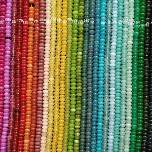 May include: A vibrant display of colorful beads arranged in vertical rows. The beads showcase a spectrum of hues, including shades of brown, pink, red, orange, yellow, green, blue, and purple. Each strand is composed of small, round beads, creating a visually appealing gradient.