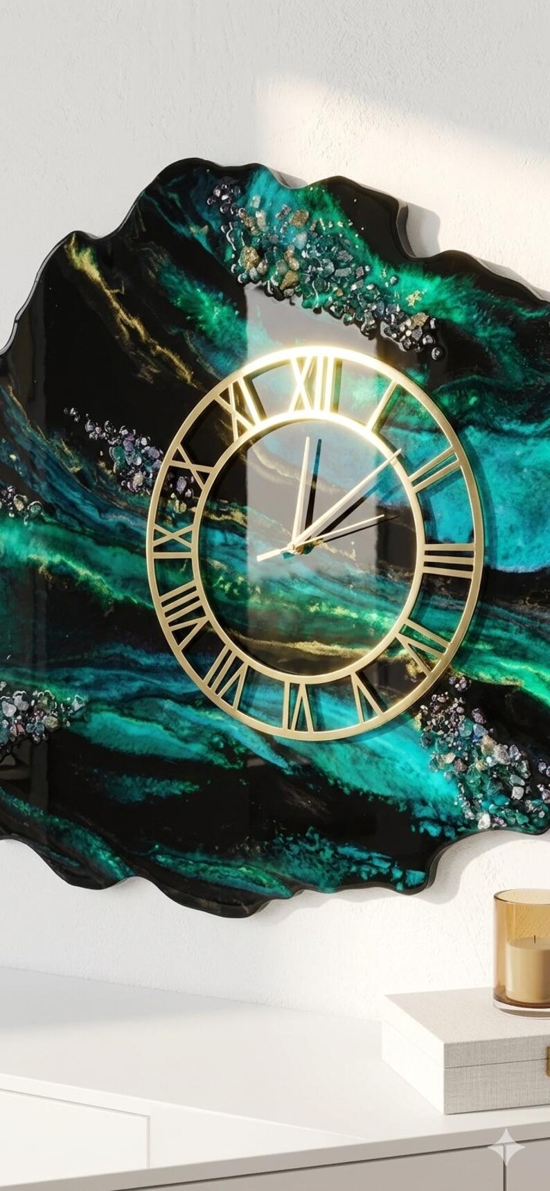 May include: A wall clock with a gold-colored frame and Roman numerals. The clock face is transparent, set against a swirling background of black, teal, and green resin. Decorative accents are scattered across the surface.