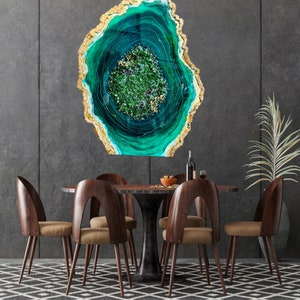May include: A green and gold resin art piece with a swirling pattern, resembling a geode, hangs on a gray wall above a wooden dining table with six chairs.