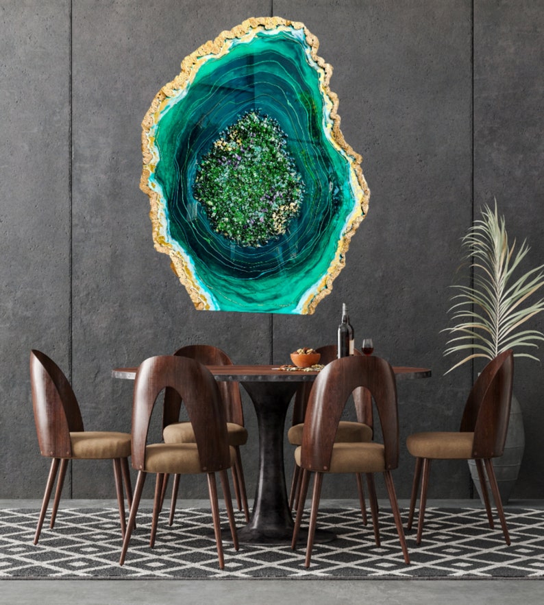 May include: A green and gold resin art piece with a swirling pattern, resembling a geode, hangs on a gray wall above a wooden dining table with six chairs.