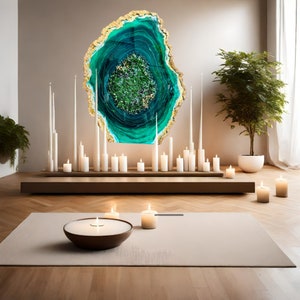 May include: A large, green and gold agate wall art piece with a swirling pattern. The art is displayed on a wall with white candles and a wooden shelf below.