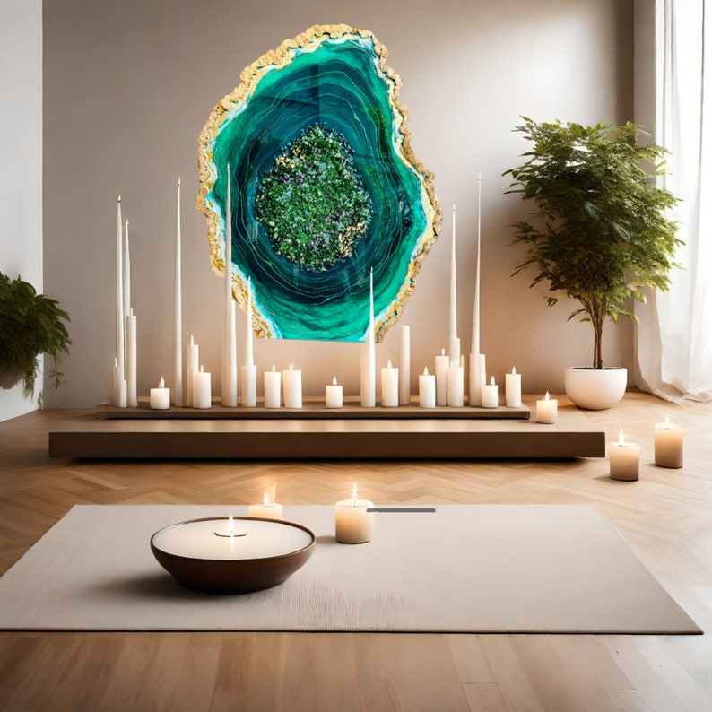 May include: A large, green and gold agate wall art piece with a swirling pattern. The art is displayed on a wall with white candles and a wooden shelf below.