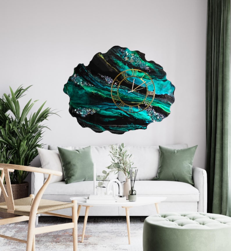 May include: A large, abstract wall clock with a gold-colored frame and Roman numerals. The clock face features a swirling pattern of teal, black, and gold colors, with glitter accents. The clock is mounted on a white wall.