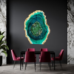 May include: A teal and gold resin art piece with a swirling pattern resembling a geode. The piece is mounted on a black wall and is surrounded by a dark wood floor.