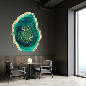 May include: A green and gold agate wall art piece with a swirling pattern. The art is hanging on a gray wall in a room with two chairs and a table.