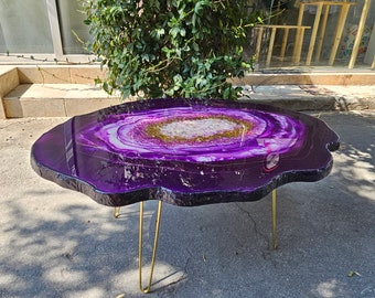 May include: Purple agate coffee table with gold metal legs. The table top is made of resin and has a unique, natural-looking pattern.