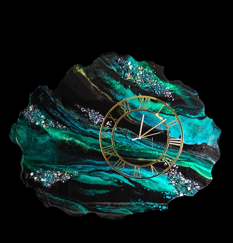 May include: A decorative wall clock with a gold-colored frame and Roman numerals. The clock is set on a unique, irregularly shaped base with a swirling pattern of black, teal, and gold colors. The base has a glossy finish and is embellished with glitter.