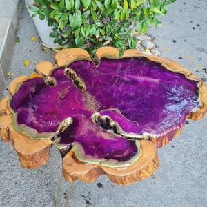 May include: A purple and gold resin coffee table with a natural wood base and gold metal legs.