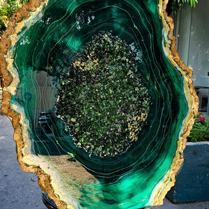 May include: A large, green, resin art piece with gold accents. The piece is shaped like a tree trunk cross-section and has a swirling, agate-like pattern.