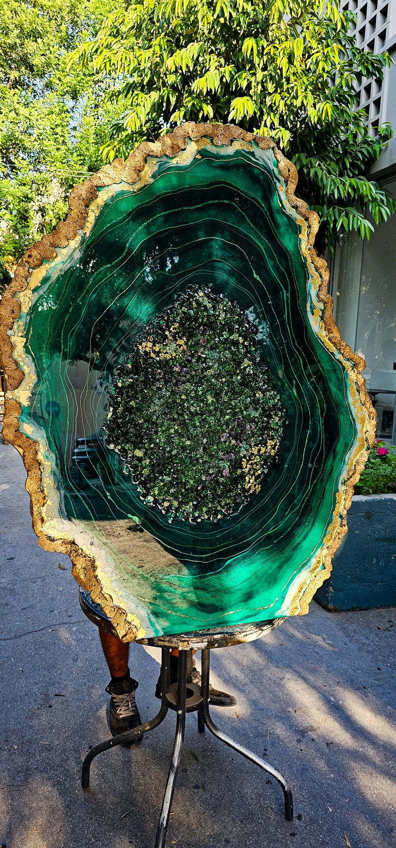 May include: A large, green, resin art piece with gold accents. The piece is shaped like a tree trunk cross-section and has a swirling, agate-like pattern.