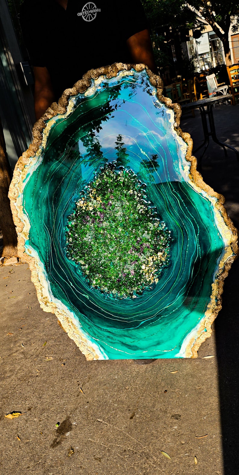 May include: A large, round, green and gold resin art piece with a swirling pattern and a center filled with green and purple glitter.