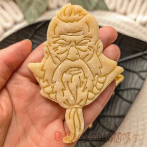 May include: A cookie cutter in the shape of a bearded man's face. The cookie cutter is made of metal and has a detailed design.