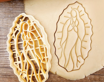 Puede incluir: Un cortador de galletas de plástico con forma de la Virgen María. El cortador se muestra sobre una masa de galletas.