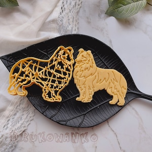 Puede incluir: Dos cortadores de galletas de plástico amarillo con forma de perro Collie. Los cortadores están en un plato negro con forma de hoja.