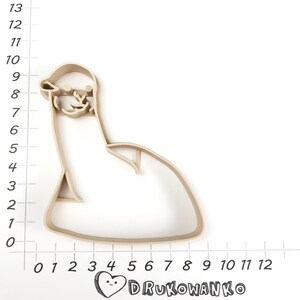 Pode incluir: Um cortador de biscoitos de pl&aacute;stico bege em forma de pinguim de desenho animado sentado. O cortador tem aproximadamente 18 cm de altura e 13 cm de largura.