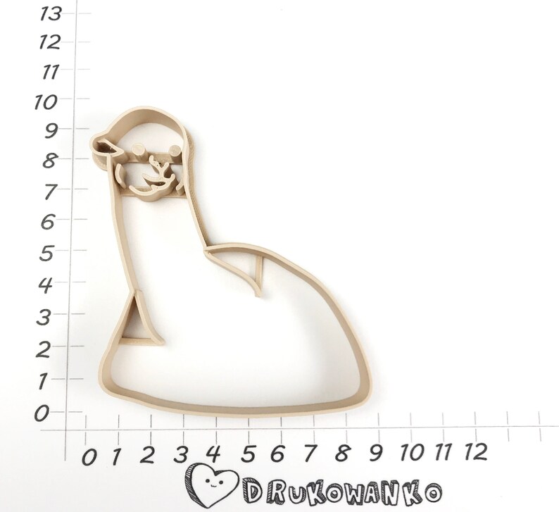 Pode incluir: Um cortador de biscoitos de pl&aacute;stico bege em forma de pinguim de desenho animado sentado. O cortador tem aproximadamente 18 cm de altura e 13 cm de largura.
