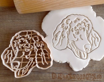 May include: A brown plastic cookie cutter in the shape of a poodle dog's head. The cutter is on a white surface with a similar design.