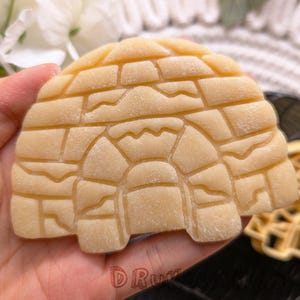 Puede incluir: Un primer plano de una masa de galleta de color marrón claro con forma de iglú. La masa tiene una superficie texturizada con un patrón de pequeños cuadrados y líneas.