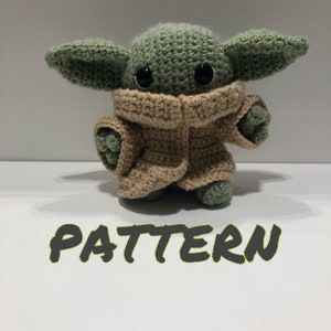 May include: Crocheted amigurumi pattern for a green and brown Baby Yoda character. The pattern includes instructions for crocheting the character's body, head, ears, and clothing.