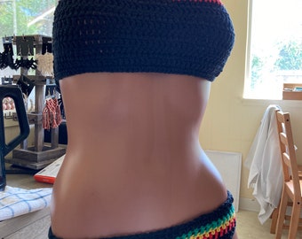 May include: A black crochet bikini top and bottom with a green, yellow, and red stripe detail. The bikini is on a mannequin.