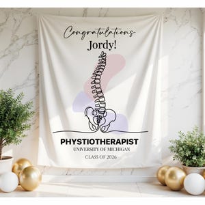 May include: A white banner with the text "Congratulations Jordy!" and a line drawing of a spine. Below the spine illustration is the text "PHYSIOTHERAPIST UNIVERSITY OF MICHIGAN CLASS OF 2026". The banner has a light pink and purple abstract design.
