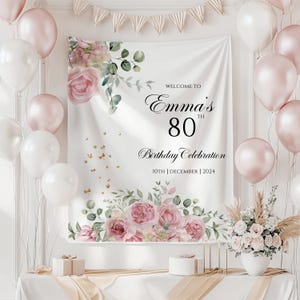 May include: White backdrop with pink floral design and gold glitter. Text reads "Welcome to Emma's 80th Birthday Celebration 10th December 2024".