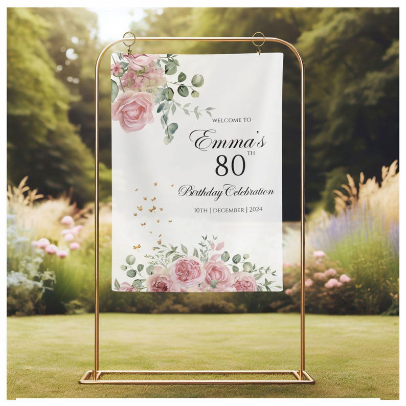 May include: Welcome to Emma's 80th Birthday Celebration, a floral-themed sign with pink roses and greenery, with the date 10th December 2024.