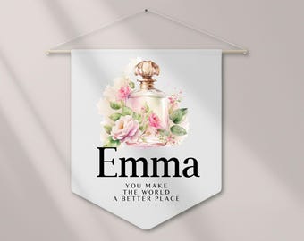 Puede incluir: Un banderín blanco con un diseño de acuarela de un frasco de perfume y rosas rosas. El nombre "Emma" está impreso en negro, con el texto "YOU MAKE THE WORLD A BETTER PLACE" debajo.