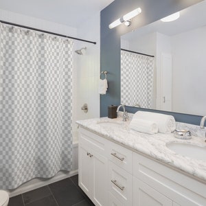 May include: A white bathroom vanity with a marble countertop and two sinks. The vanity has two drawers and two doors. There is a shower curtain behind the vanity.